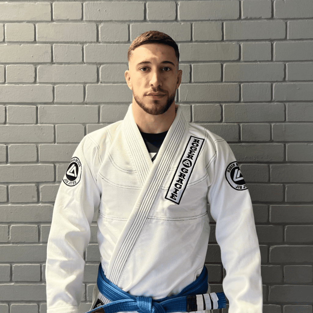 Blue belt male assistant coach smiling at the camera in his Gi.